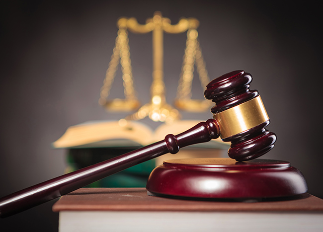 side of a judge's hammer with golden scale in the background, law and justice concept